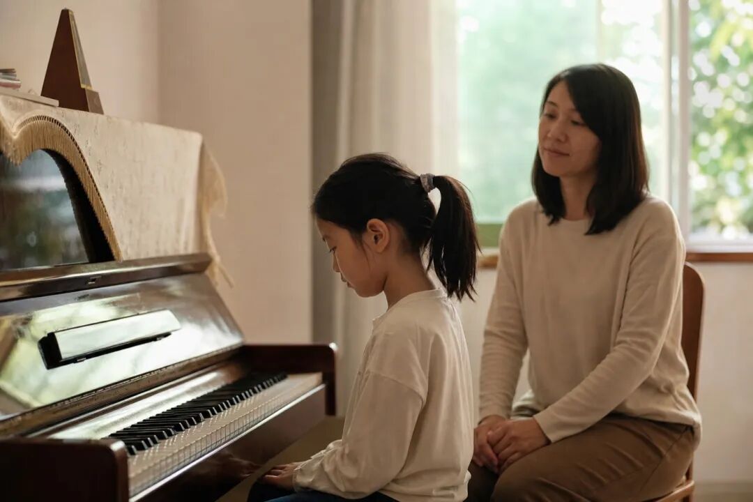 A parent lowers their hands, giving the child space to assess the sound independently